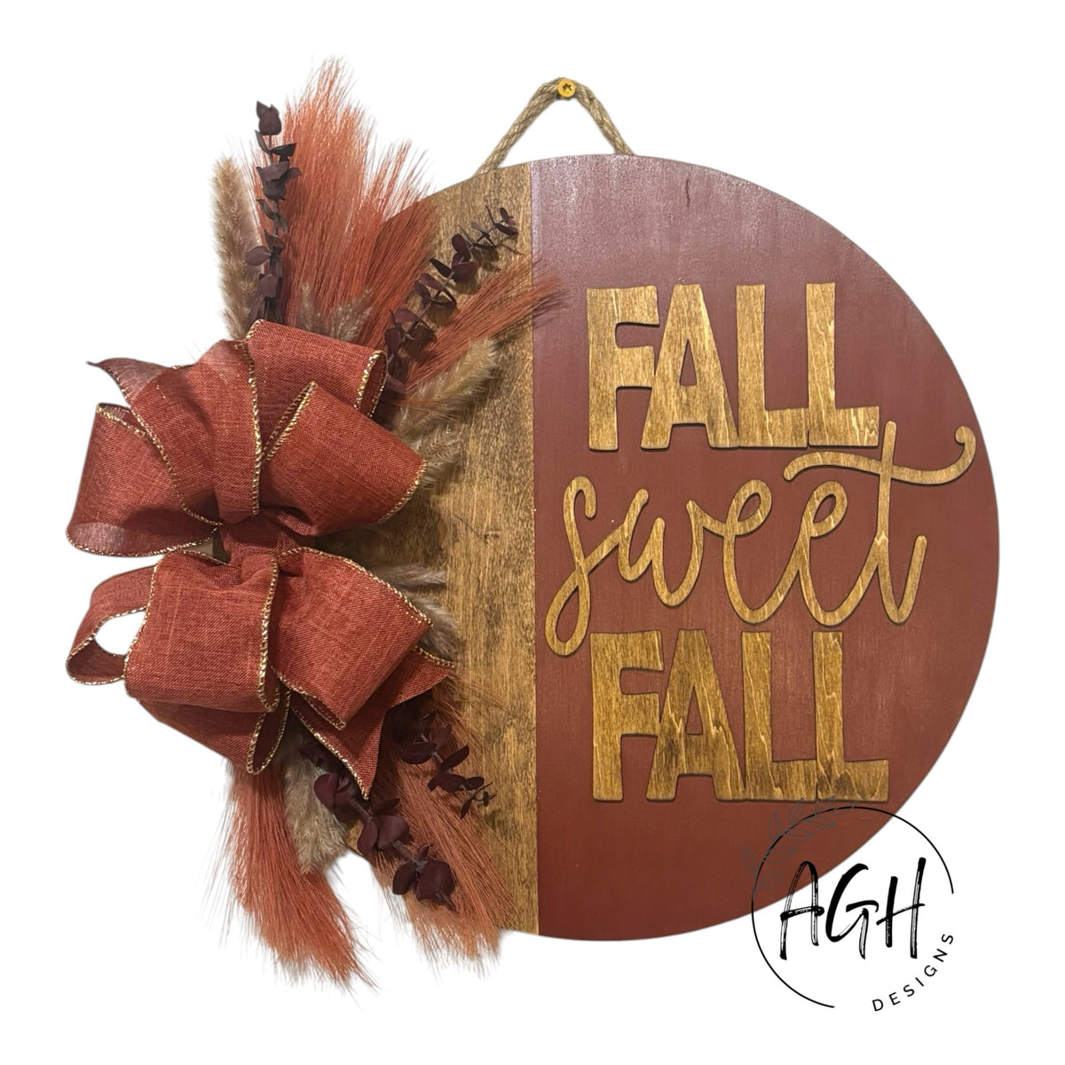 AGH Designs circular wooden fall wall sign with Fall Sweet Fall text, burlap bow, and dried pampas grass foliage.