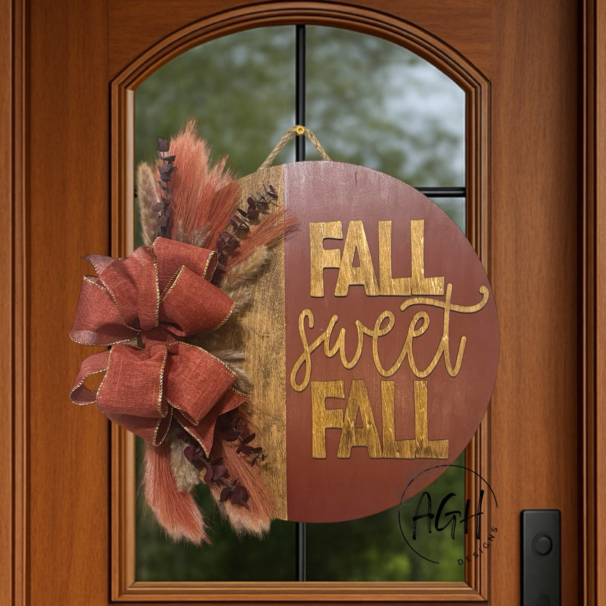 AGH Designs round wooden Fall Sweet Fall door sign with burgundy and natural wood finish, bow, and autumn foliage.